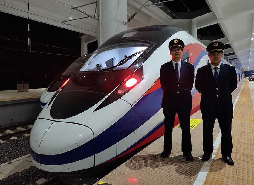 劉銀能（右一）與中國(guó)師父鄔俊鴻在動(dòng)車組前合影。受訪者供圖