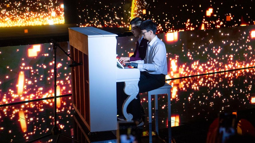 智能仿生手使用者古月與少年鋼琴家舒海峰合奏。主辦方供圖